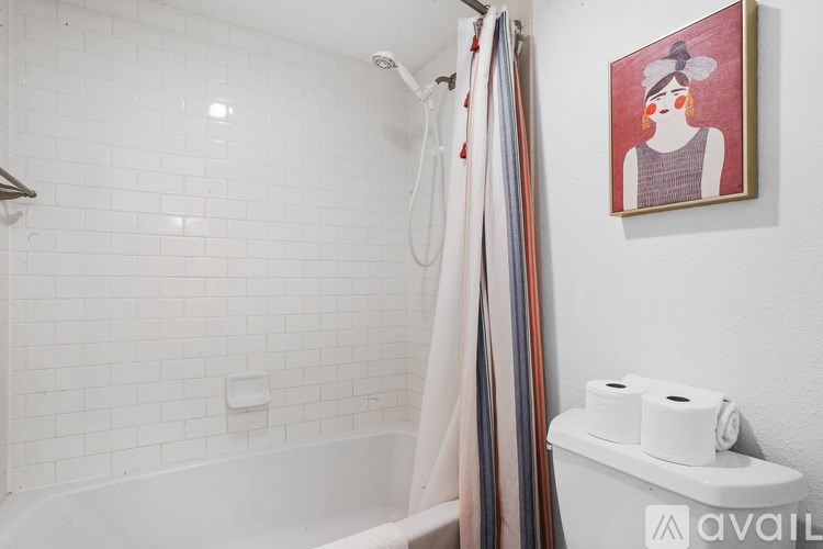 A bathroom with a white tub and a picture of a woman on the wall.