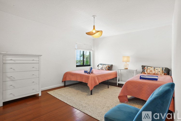 A bedroom with two beds and a blue chair.