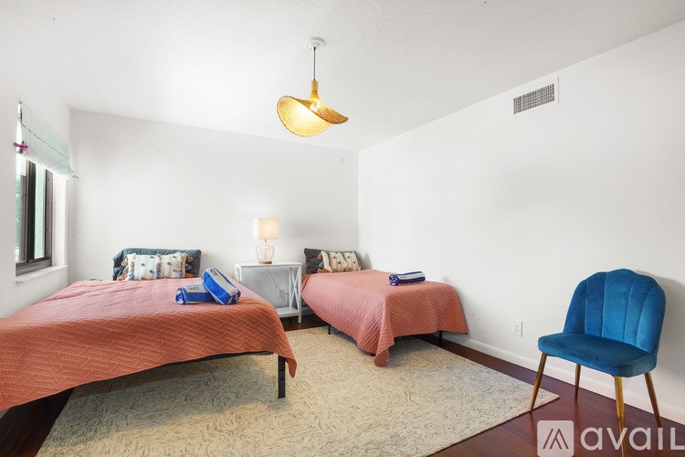 A bedroom with two beds and a blue chair.