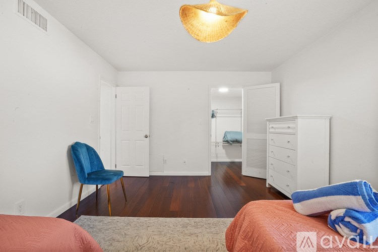 A room with a blue chair and a white wardrobe.