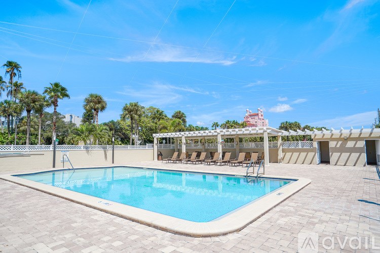 A swimming pool surrounded by a tiled floor and lounge chairs under a canopy.