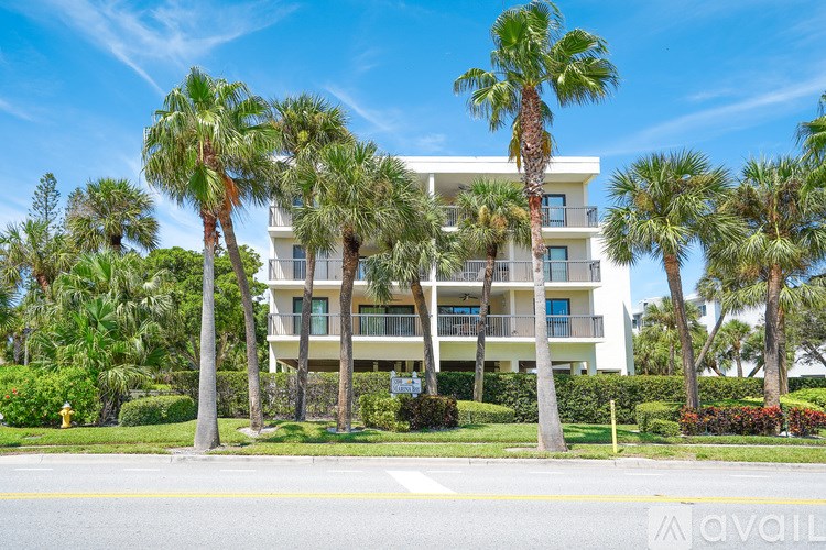 A building with a balcony is surrounded by palm trees.
