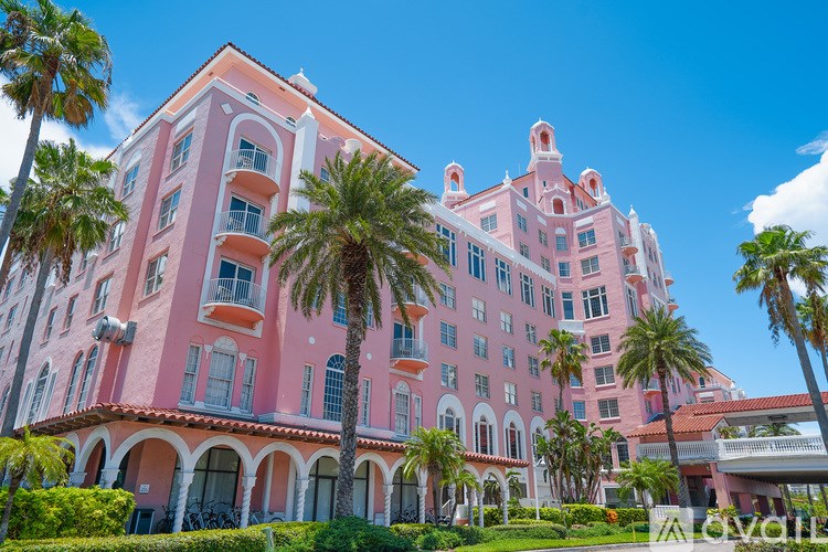 A pink building with palm trees in front.