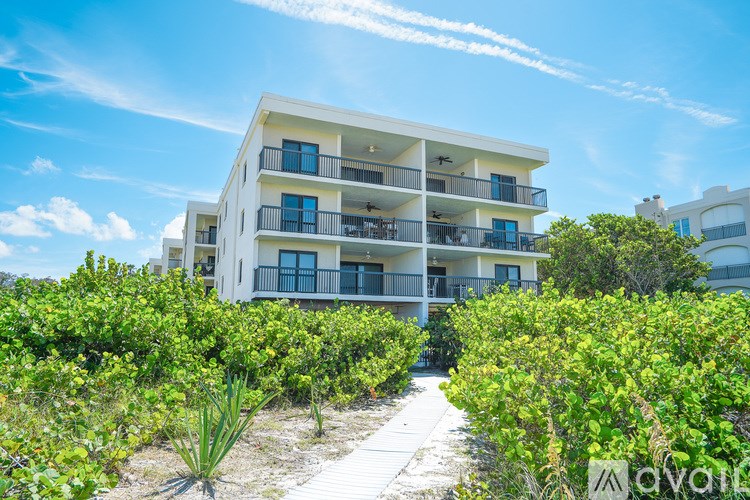 A white apartment building with balconies and a pathway leading to it.