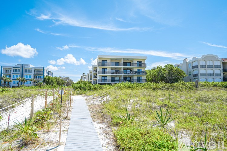 A boardwalk leads through a grassy area to a row of houses.