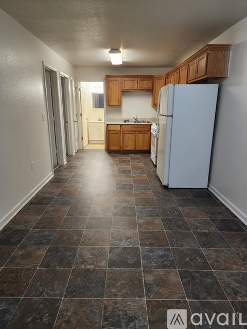 A kitchen with a white refrigerator and brown cabinets.