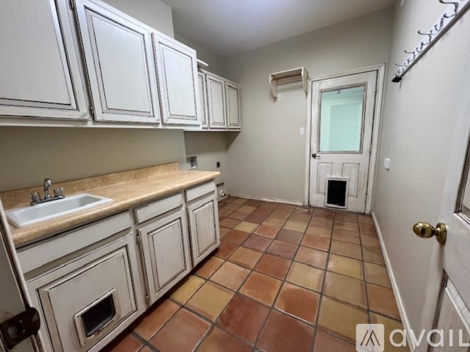 A kitchen with white cabinets and a tiled floor.