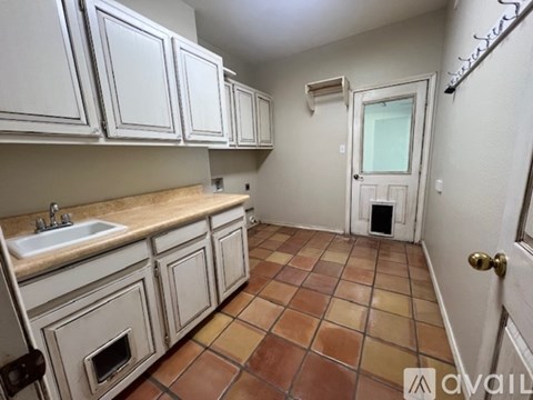 A kitchen with white cabinets and a tiled floor.