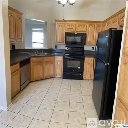 A kitchen with wooden cabinets and black appliances.