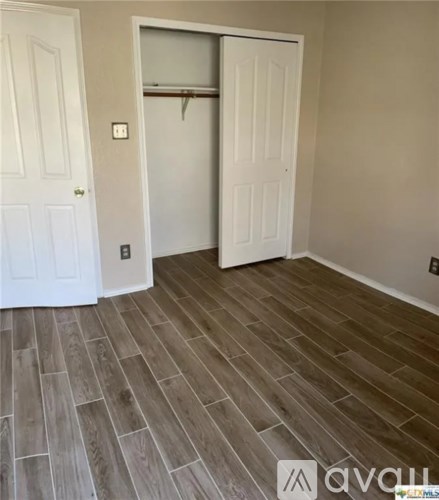 A room with a white door and a wooden floor.