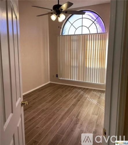 A room with wooden flooring and a ceiling fan.