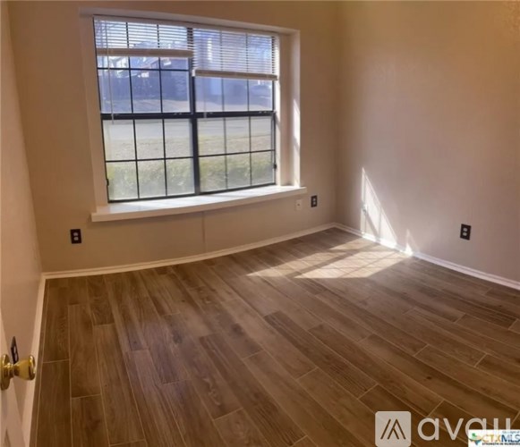 A room with a window and wooden flooring.