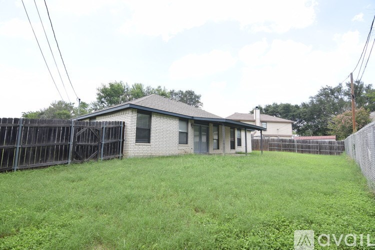 A house with a fence and green grass in front.