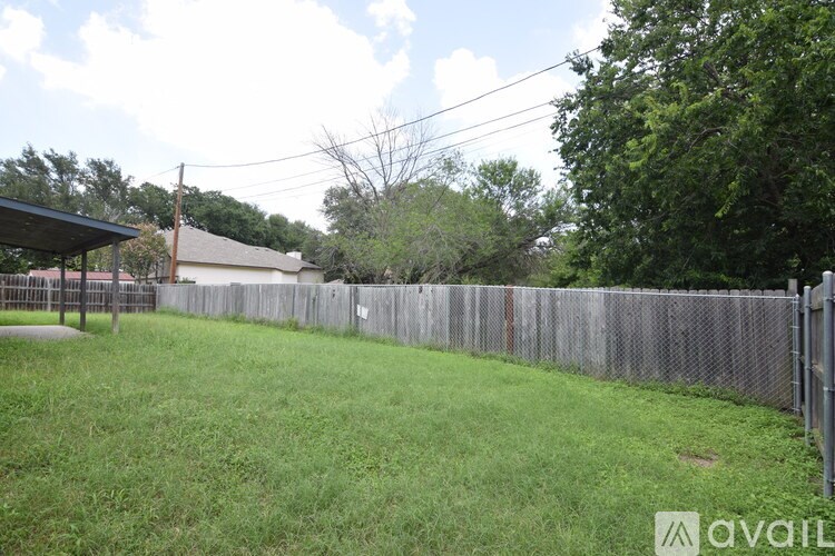 A backyard with a fence and a covered patio.