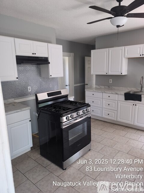 A kitchen with a black stove top oven and white cabinets.