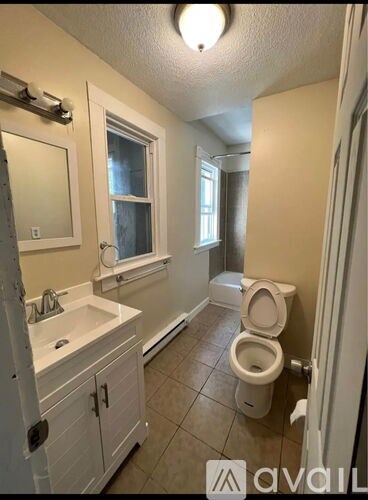 A bathroom with a toilet, sink, and mirror.