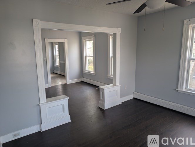 A room with a mirror, a window, and a wooden floor.