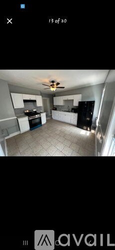 A spacious kitchen with white cabinets and a black refrigerator.