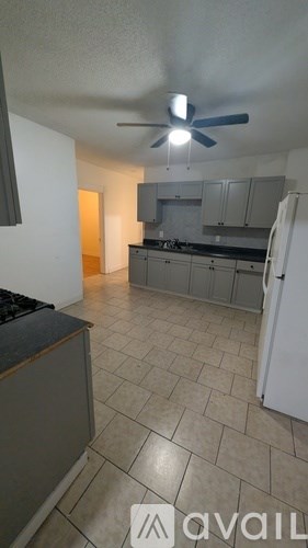 A kitchen with a fan on the ceiling and a refrigerator on the right side.