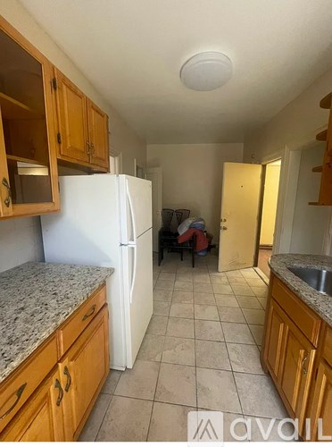 A kitchen with a white refrigerator and wooden cabinets.