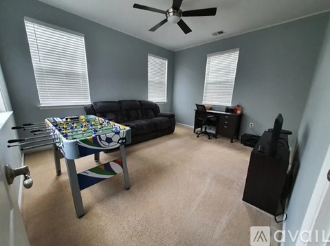A living room with a black couch, a fan, and a table with a colorful tablecloth.
