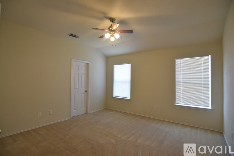 A room with a ceiling fan and a window with blinds.