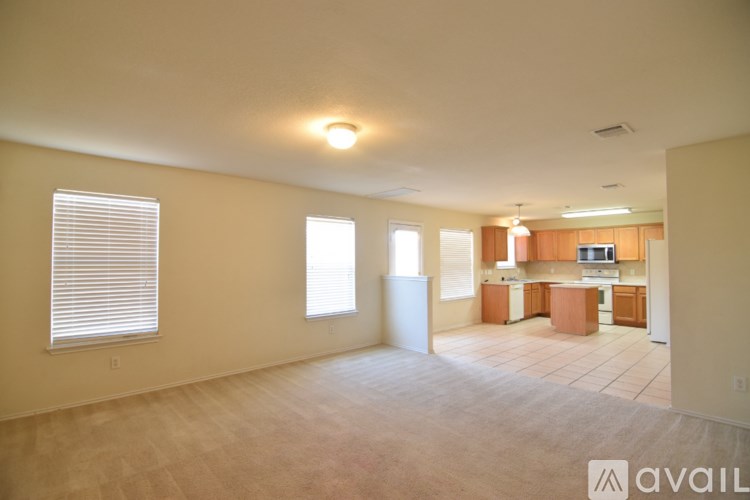A spacious living room with a kitchen in the background.