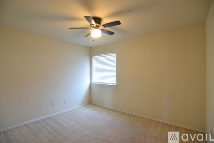 A room with a ceiling fan and a window with blinds.
