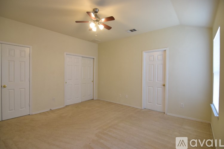 A room with a ceiling fan and three doors.