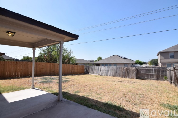 A backyard with a patio and a fence.