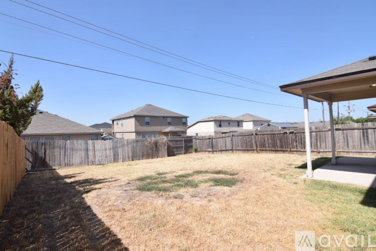 A backyard with a wooden fence and a house in the background.