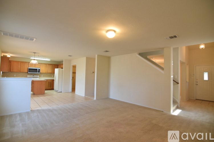 A spacious living room with a kitchen area in the background.