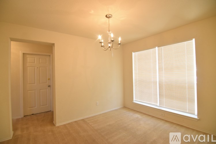 A room with a chandelier, a door, and a window with blinds.