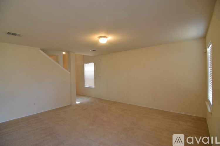 A spacious room with wooden flooring and a window on the right side.