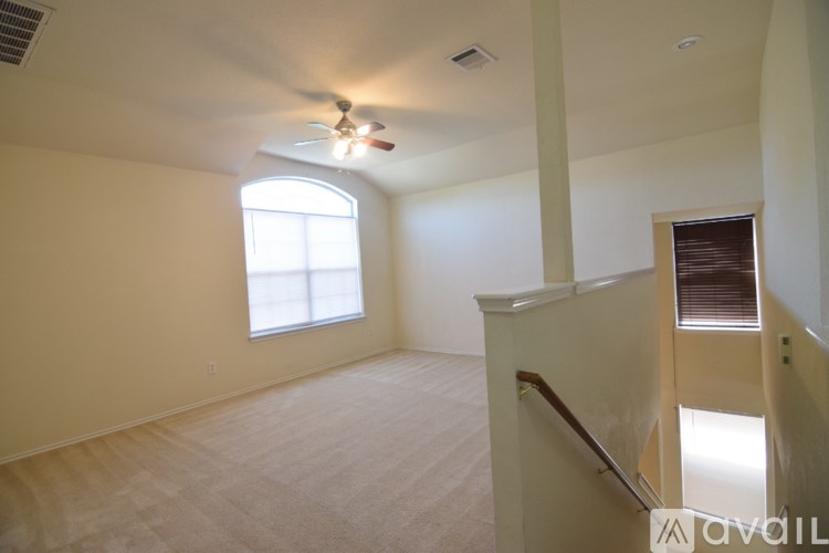 A room with a fan, a window, and a staircase.