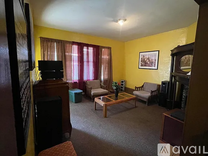 A living room with a yellow wall and a television.