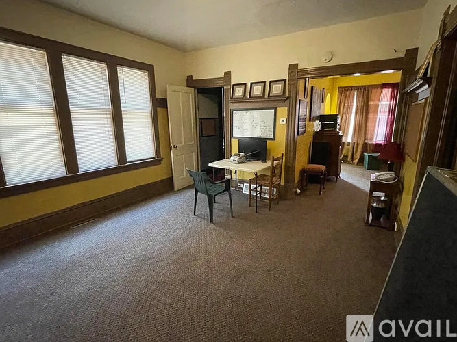 A room with a carpeted floor and a desk with a chair.