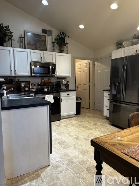 A kitchen with white cabinets and a black countertop.