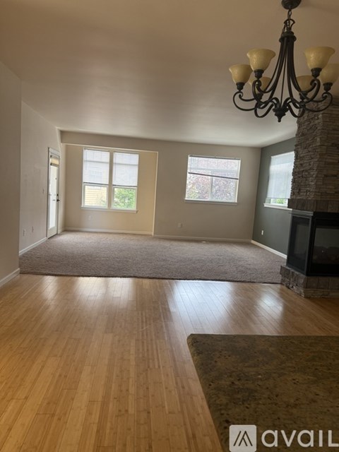 A living room with a chandelier, a fireplace, and a rug on the floor.