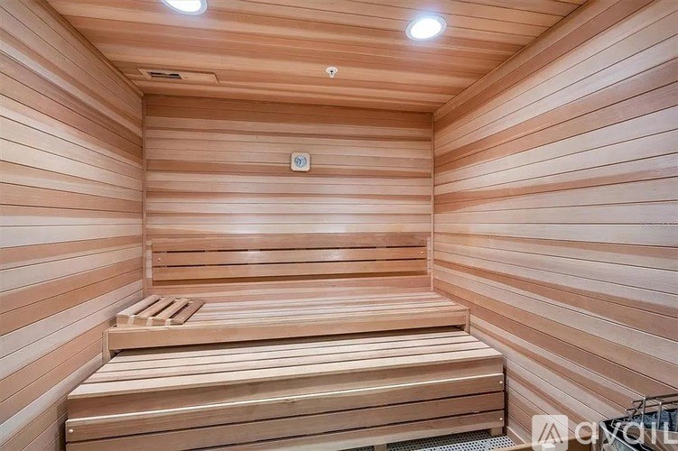 A wooden sauna with benches and lights on the ceiling.