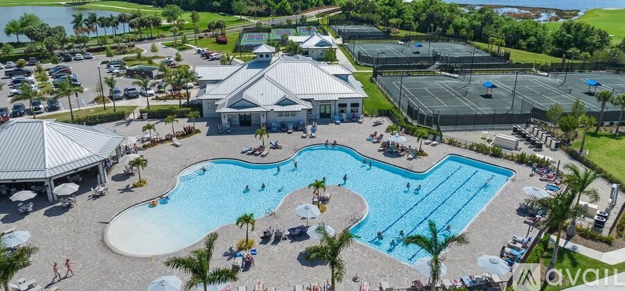 A large outdoor swimming pool surrounded by a grassy area and a pavilion.