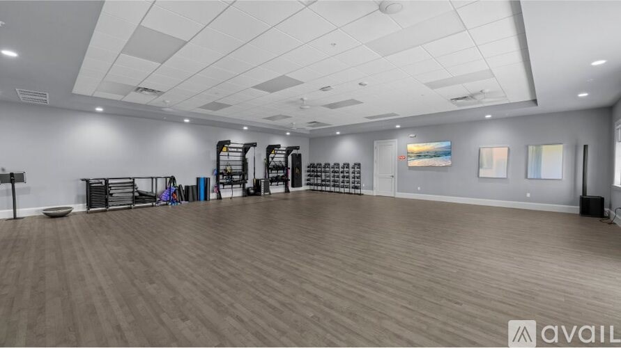 A spacious room with wooden flooring and a variety of exercise equipment.