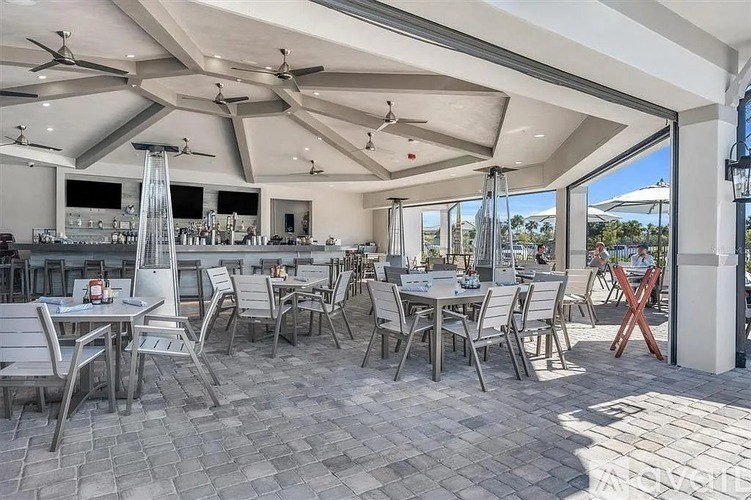 A patio with tables and chairs and a ceiling fan.