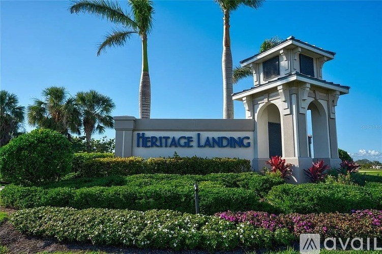 A sign for Heritage Landing is surrounded by greenery and a small tower.
