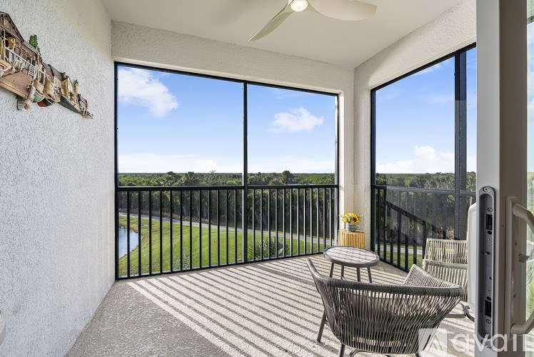 A balcony with a table and chairs overlooking a green field.