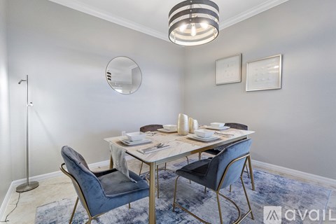 A dining room with a round mirror on the wall and a table set for two.