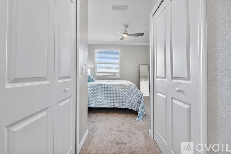 A bedroom with a bed, a ceiling fan, and a window with blinds.