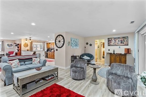 A living room with a grey sofa, a grey armchair, a grey chair and a grey coffee table.