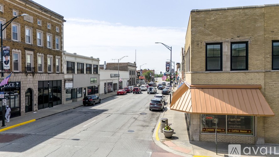 A street view of a city with buildings on either side and cars driving down the road.