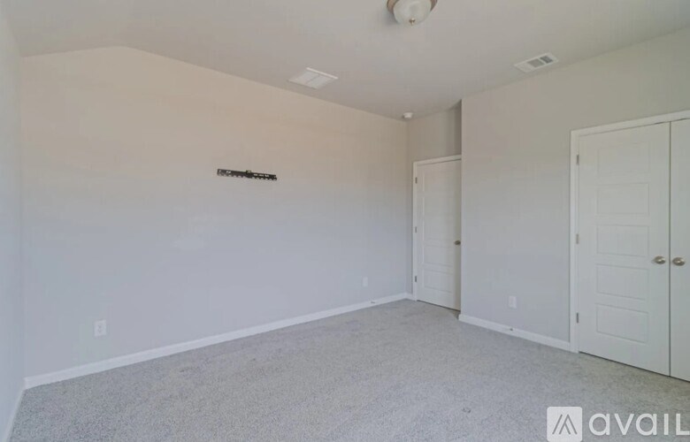 A room with white walls and carpeted floor with a sign on the wall.